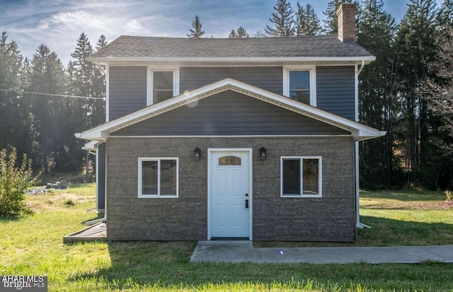 view of front facade featuring a chimney, a front lawn, and roof with shingles