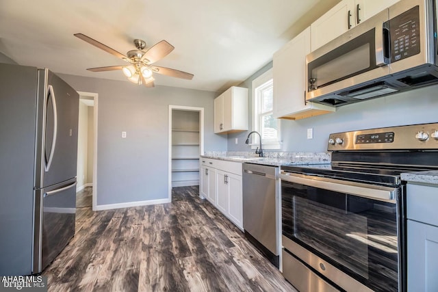 kitchen with dark wood finished floors, white cabinets, appliances with stainless steel finishes, and a sink