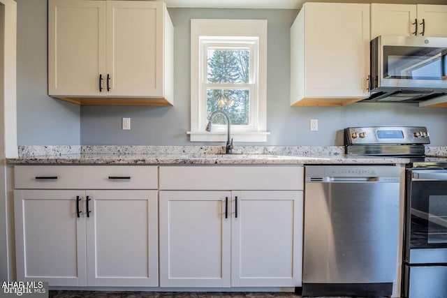 kitchen featuring a sink, white cabinets, light stone counters, and stainless steel appliances