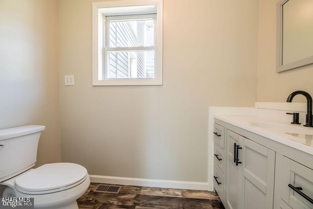 bathroom with vanity, toilet, wood finished floors, and baseboards