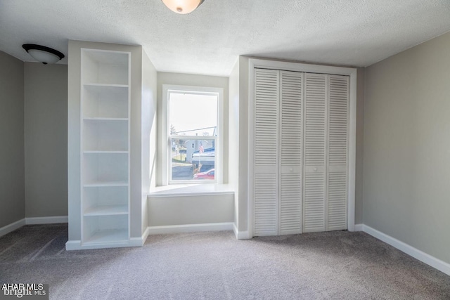 unfurnished bedroom featuring baseboards, carpet floors, a textured ceiling, and a closet