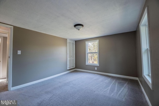 carpeted empty room with baseboards and a textured ceiling