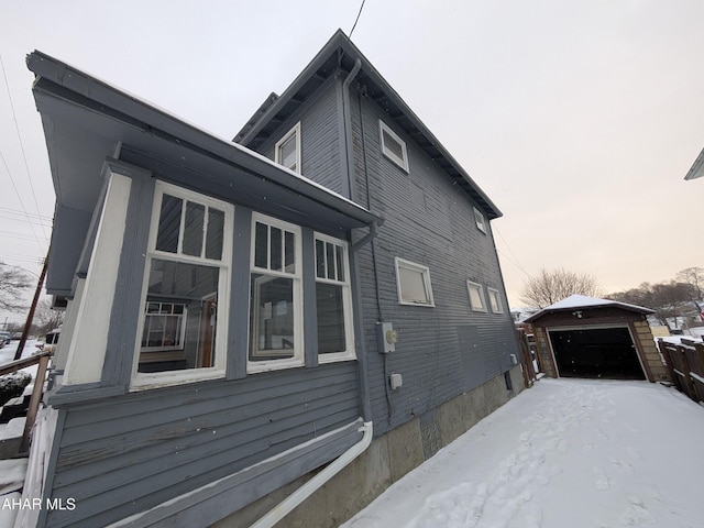 view of snow covered exterior featuring an outbuilding and a garage