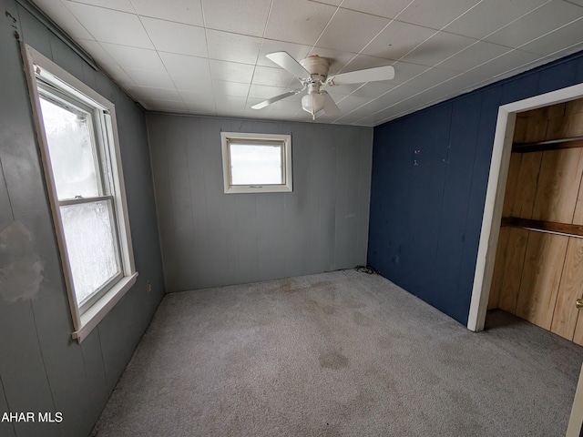 carpeted empty room featuring a healthy amount of sunlight and ceiling fan