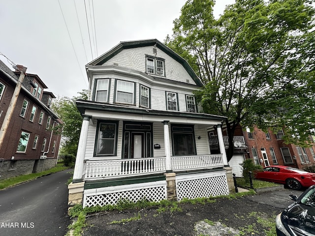 view of front facade with covered porch and a gambrel roof