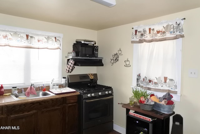 kitchen featuring dark brown cabinetry, stainless steel gas stove, exhaust hood, and sink