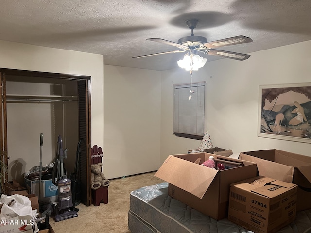 carpeted bedroom featuring ceiling fan, a textured ceiling, and a closet