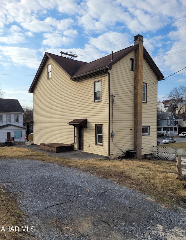 view of property exterior featuring a chimney and fence