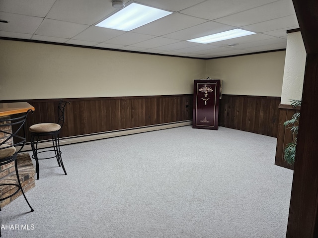 interior space featuring a paneled ceiling, light colored carpet, and bar area