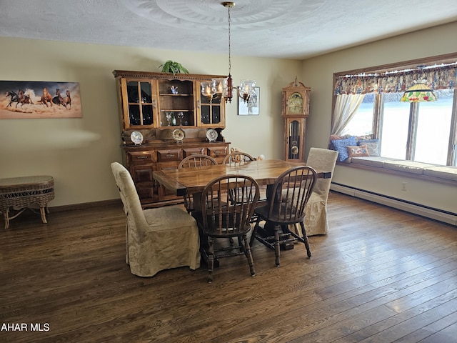 dining space featuring dark wood-type flooring, a textured ceiling, an inviting chandelier, and baseboard heating