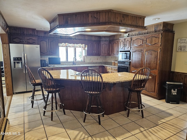 kitchen with sink, backsplash, a kitchen bar, stainless steel appliances, and light tile patterned flooring