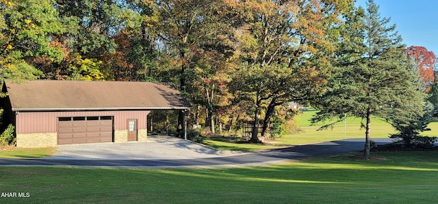 view of front of house featuring a garage, an outdoor structure, a carport, and a front lawn