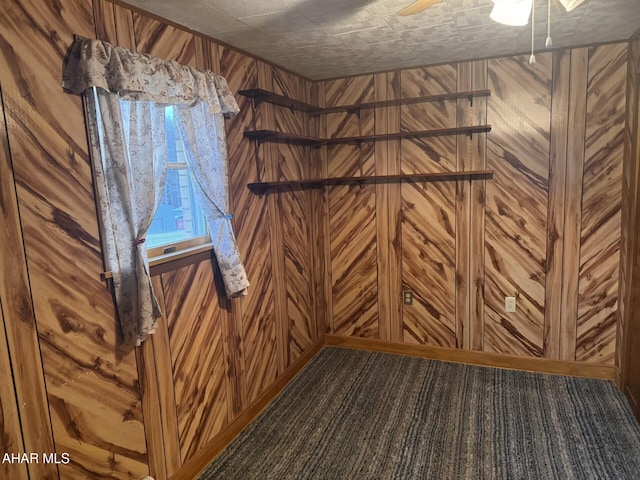 interior space featuring carpet, ceiling fan, and wood walls