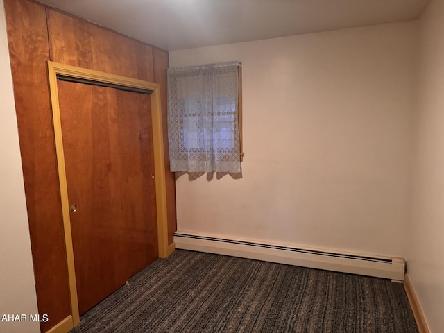 unfurnished bedroom featuring a closet, a baseboard radiator, and dark carpet