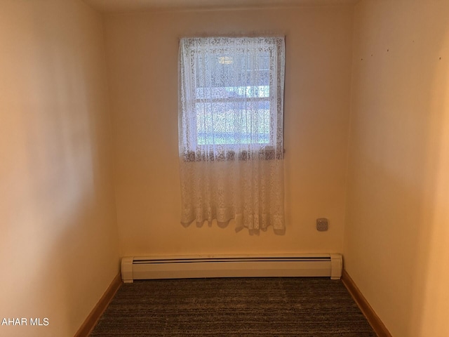 carpeted spare room featuring a baseboard heating unit