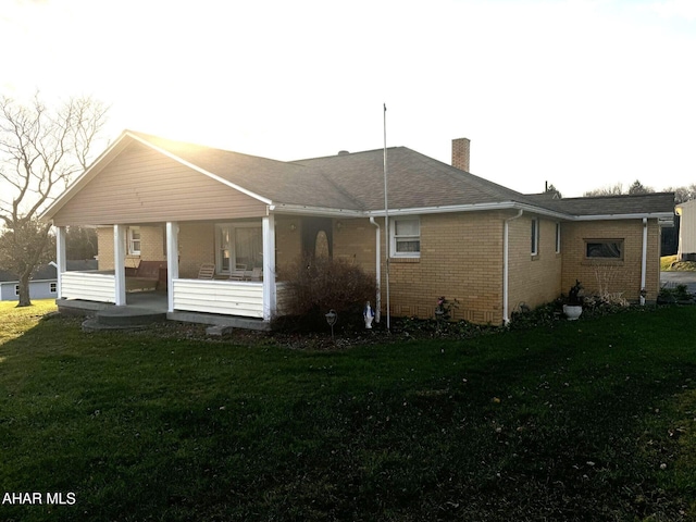 back of house featuring covered porch and a yard