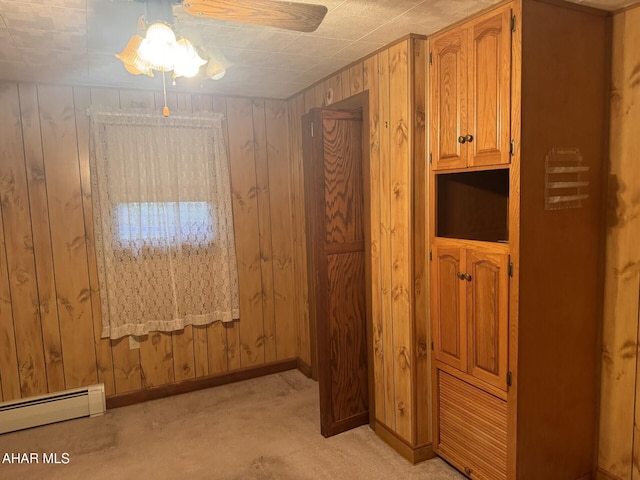 interior space featuring ceiling fan, baseboard heating, and wooden walls