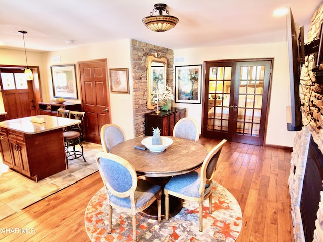 dining space featuring plenty of natural light, french doors, and light hardwood / wood-style flooring