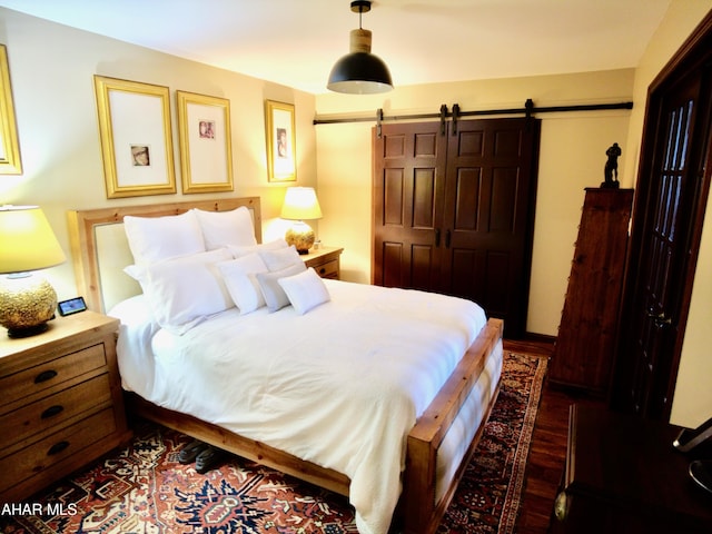 bedroom with a barn door, dark hardwood / wood-style flooring, and a closet