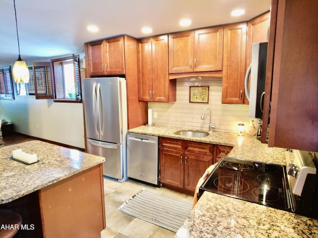 kitchen featuring hanging light fixtures, light stone countertops, sink, and stainless steel appliances