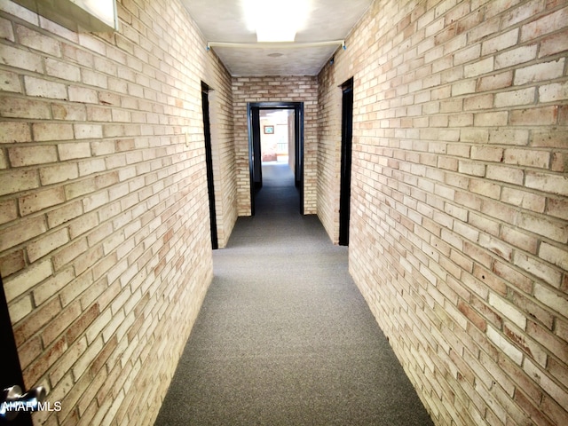 hallway with carpet floors and brick wall