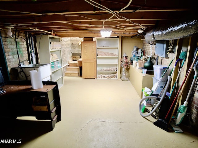 basement featuring electric panel and brick wall