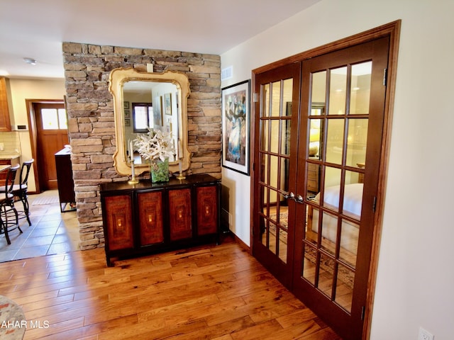 corridor with french doors and light hardwood / wood-style flooring