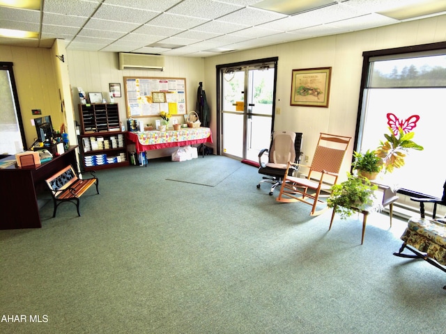 interior space with a paneled ceiling, carpet floors, and a wall unit AC