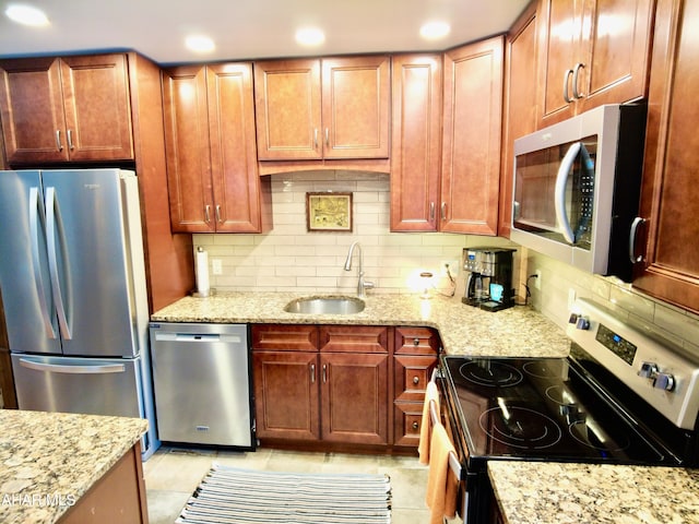 kitchen with sink, light tile patterned floors, light stone countertops, appliances with stainless steel finishes, and tasteful backsplash