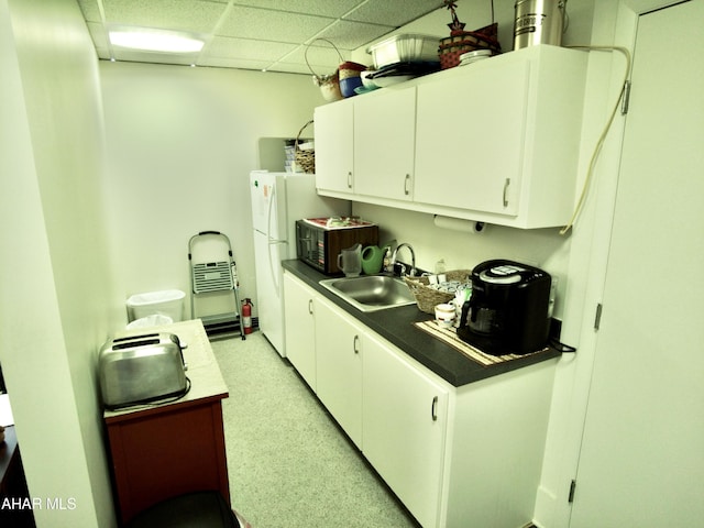 kitchen featuring white cabinets, white refrigerator, a drop ceiling, and sink