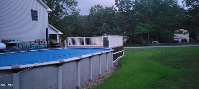 view of swimming pool featuring a lawn and a wooden deck