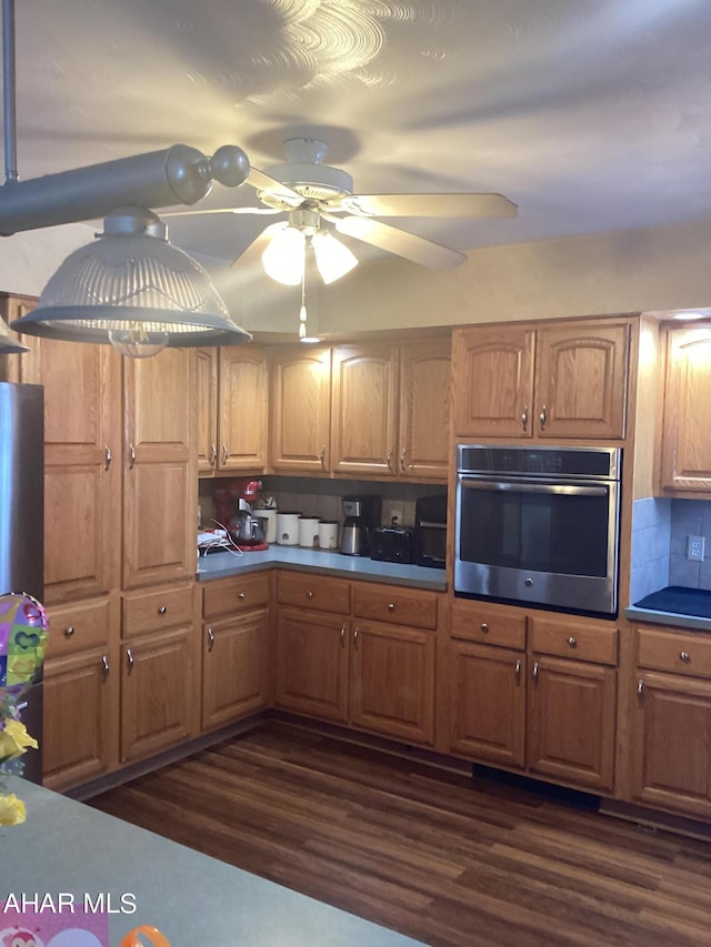 kitchen with dark hardwood / wood-style floors, oven, tasteful backsplash, and ceiling fan