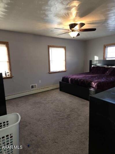 carpeted bedroom with ceiling fan and baseboard heating