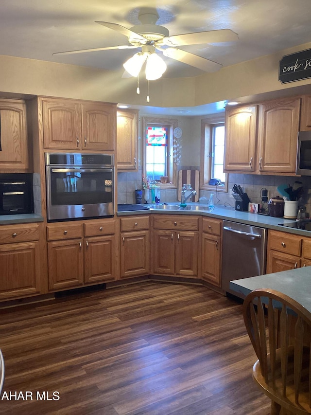 kitchen featuring ceiling fan, sink, dark hardwood / wood-style flooring, decorative backsplash, and appliances with stainless steel finishes