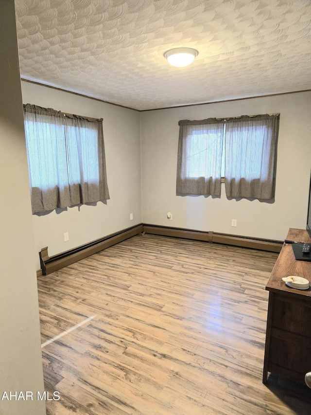 spare room featuring a textured ceiling, light wood-type flooring, and baseboard heating