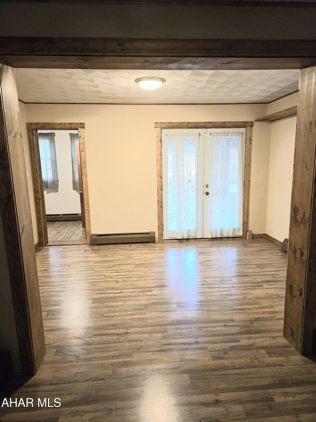 unfurnished room featuring beamed ceiling, french doors, hardwood / wood-style flooring, and a baseboard heating unit