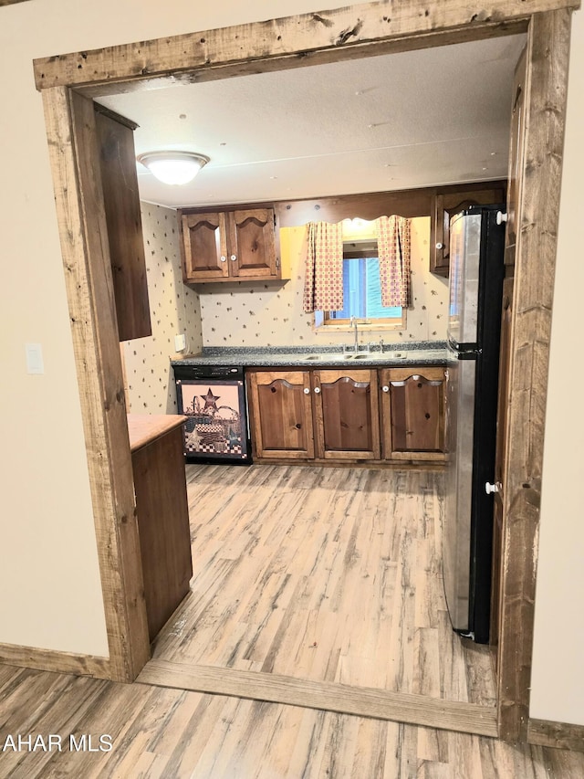 kitchen with stainless steel fridge, sink, and light hardwood / wood-style floors