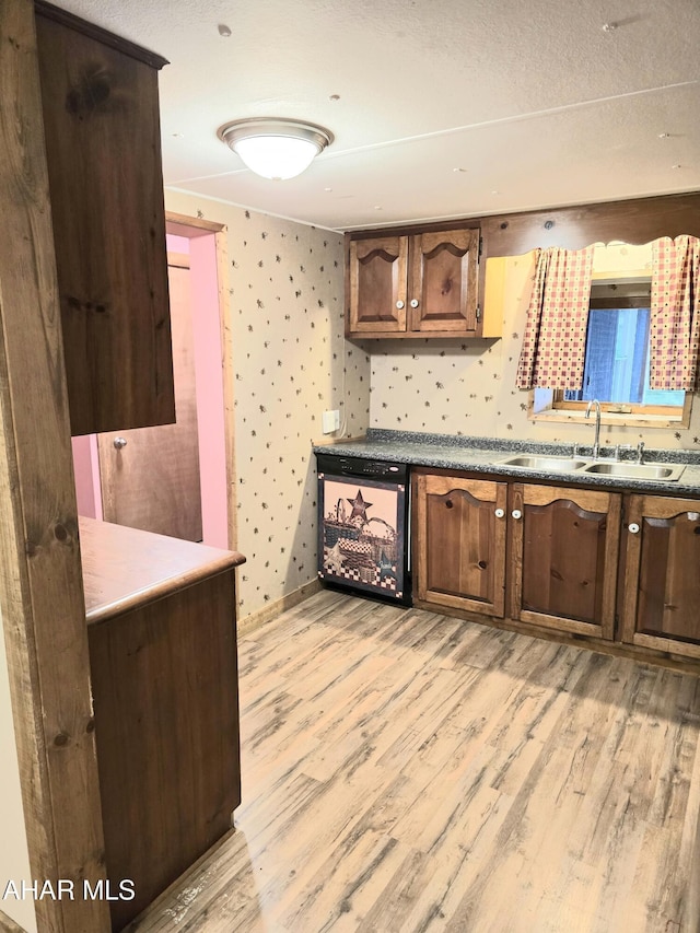 kitchen featuring dishwasher, a textured ceiling, light hardwood / wood-style flooring, and sink