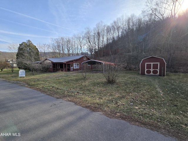 view of front of property featuring a lawn, a carport, and a storage shed