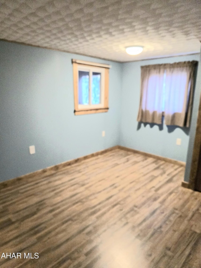 unfurnished room featuring hardwood / wood-style flooring, a textured ceiling, and a wealth of natural light