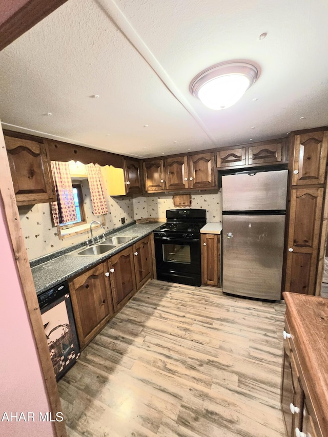 kitchen featuring black gas stove, sink, stainless steel fridge, dark brown cabinets, and light hardwood / wood-style floors