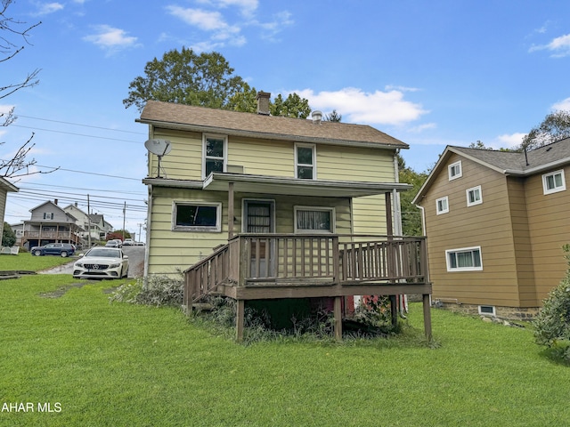 back of house featuring covered porch and a yard