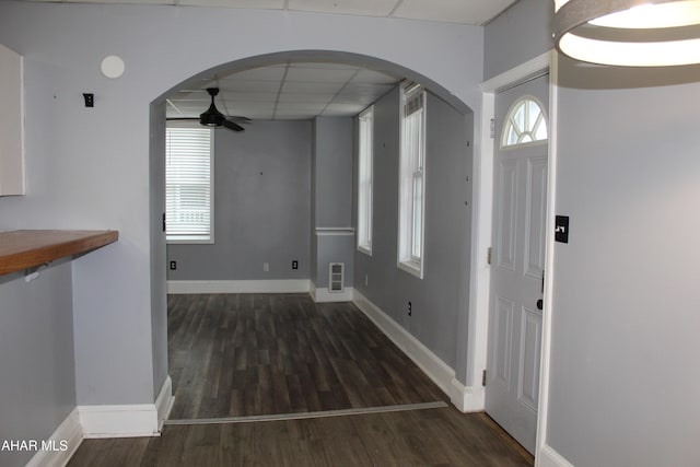 interior space with a paneled ceiling, ceiling fan, and dark hardwood / wood-style floors