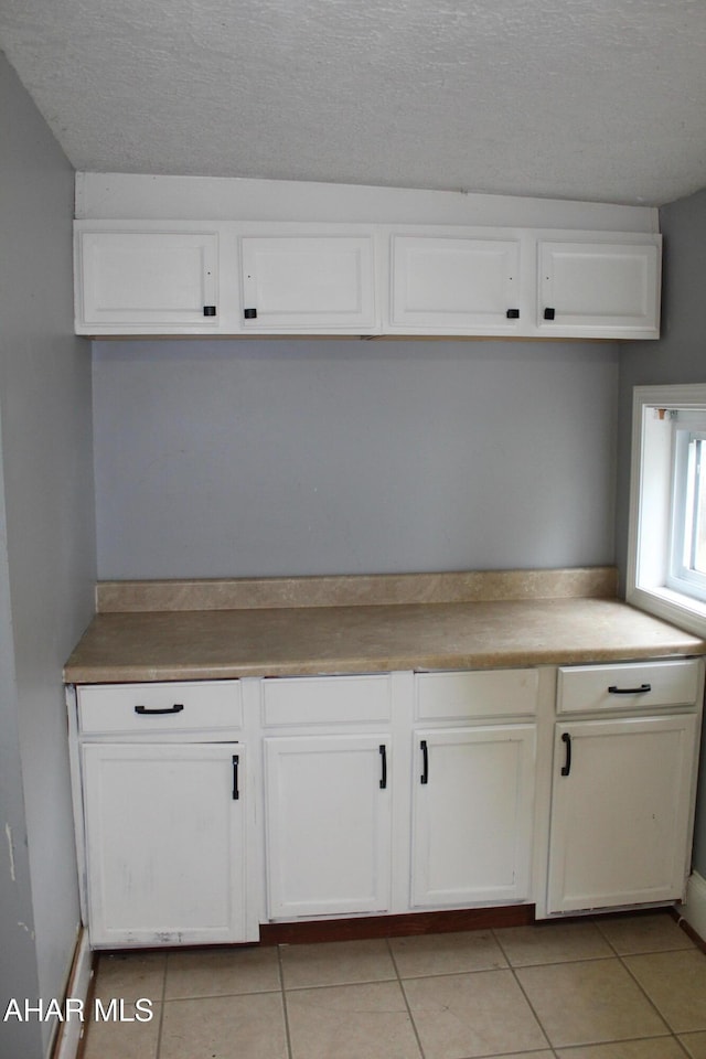 kitchen featuring white cabinetry, light tile patterned floors, and a textured ceiling