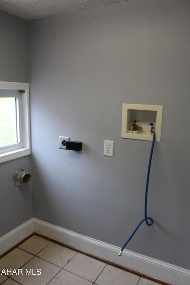 clothes washing area with washer hookup, light tile patterned floors, and a textured ceiling