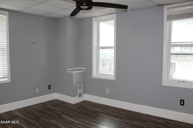 spare room with a paneled ceiling, ceiling fan, dark hardwood / wood-style flooring, and a wealth of natural light