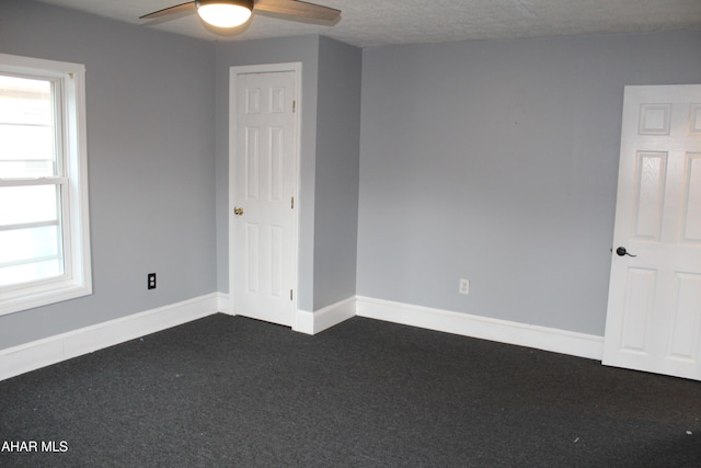 carpeted empty room featuring a textured ceiling, ceiling fan, and a healthy amount of sunlight