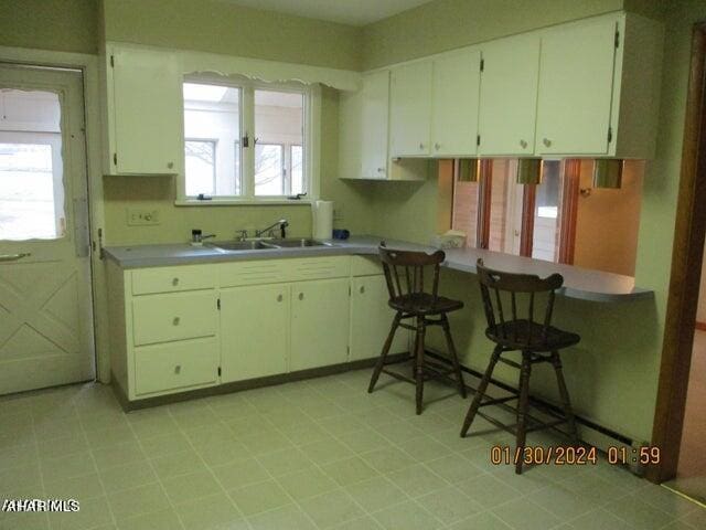 kitchen featuring plenty of natural light, white cabinetry, sink, and kitchen peninsula