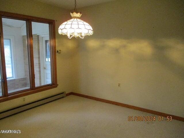 spare room with a chandelier, carpet floors, and a baseboard radiator