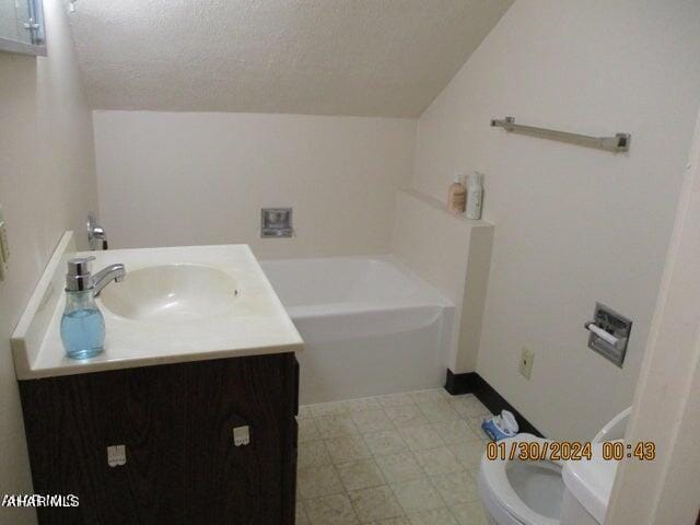 bathroom with a bathtub, vanity, a textured ceiling, and toilet